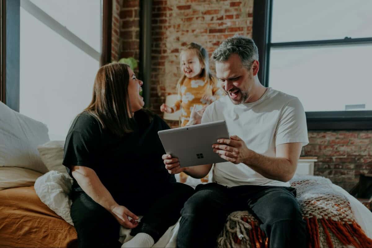 a man and woman sitting on a couch looking at a laptop